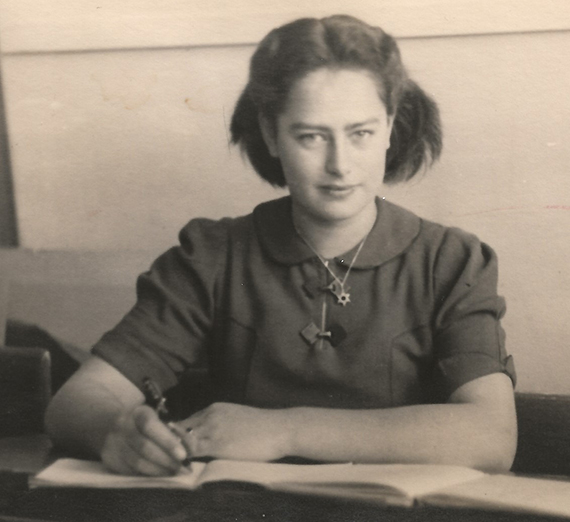 Woman sits holding a pencil. 