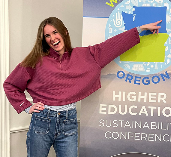 Claire Booth points to Spokane's location on the Spokane Oregon Higher Education Sustainability Conference logo 
