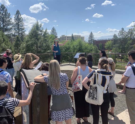 A person is speaking to a large group of people in an outdoor setting.