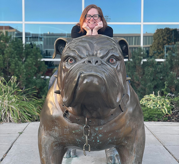 Femal sitting with chin in hands on Spike the bulldog statue