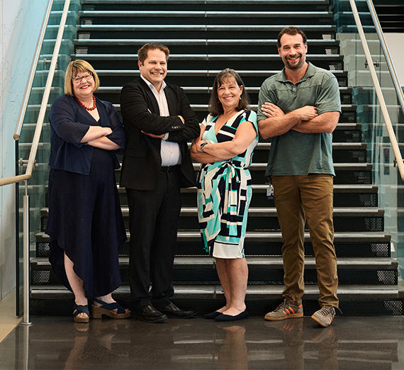 two women and two men stand on stairs