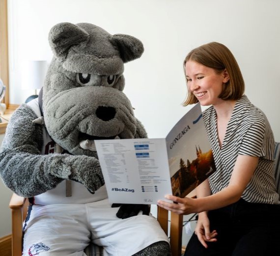 Spike and an admission counselor sitting together looking at a Gonzaga visit folder.