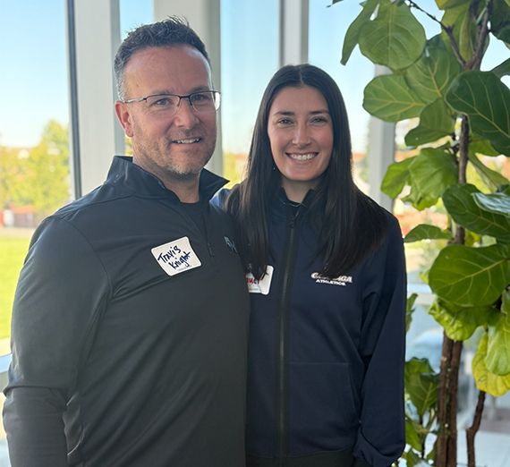 Two people smile standing next to each other.