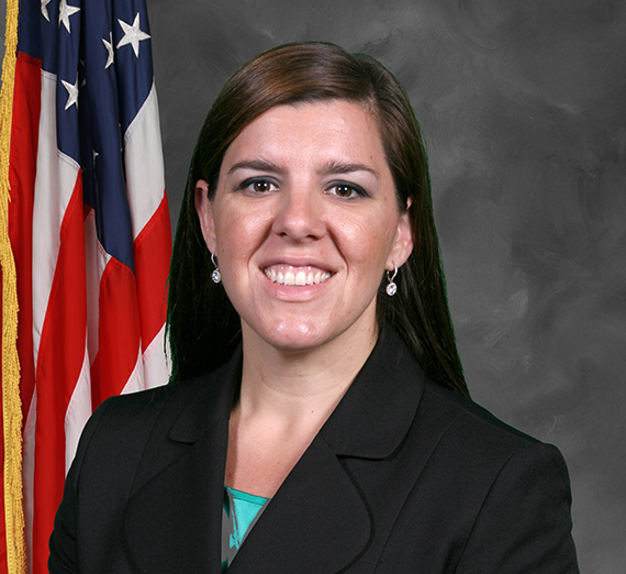 Carrie Braun in front of a grey background and American flag 