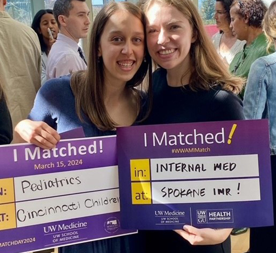 Two girls holding up sings with the hospitals they were matched with.