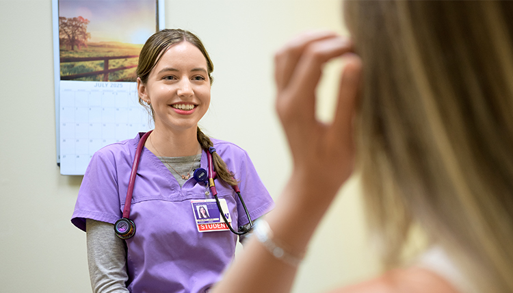 female medical student visits with patient in clinic