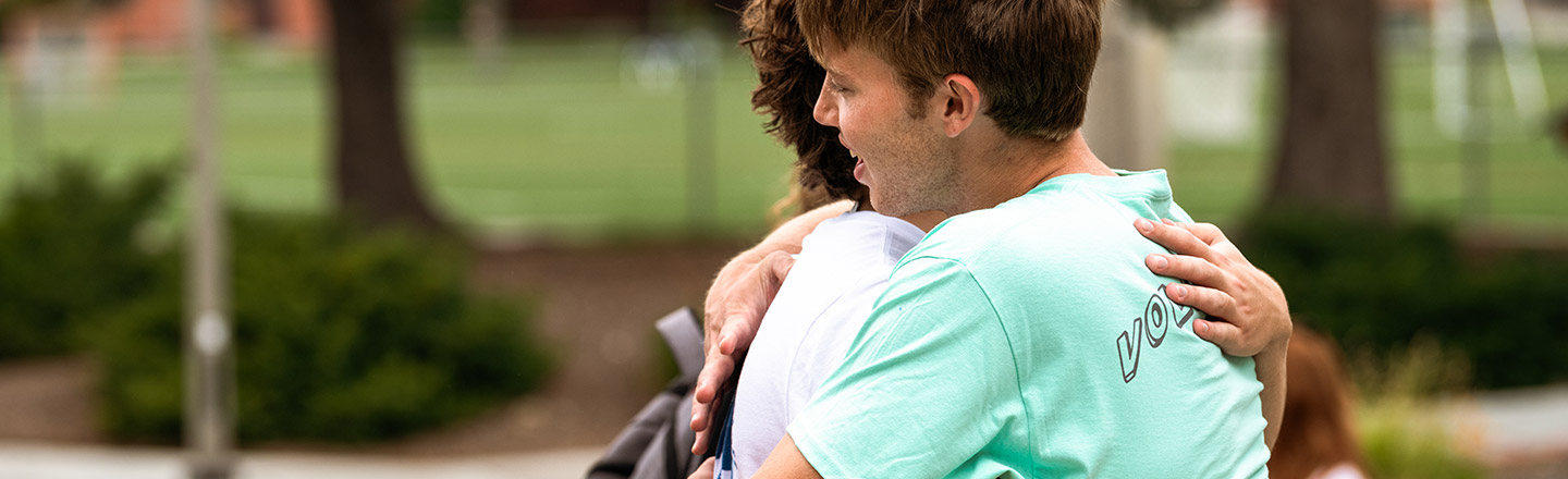 two students hugging on CM lawn