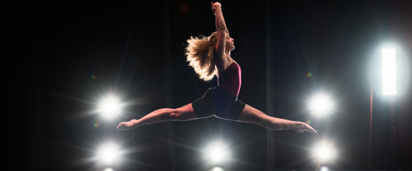Dancer leeping across an illuminated stage.