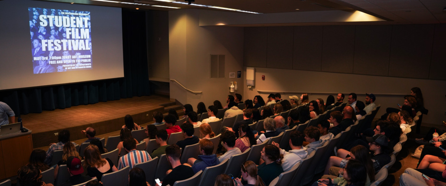 An auditorium filled with people viewing a screen that says Student Film Festival.