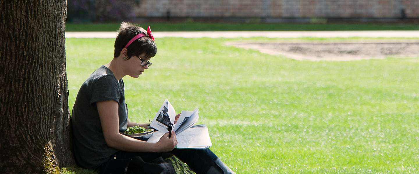 Student sitting at treen on Herak lawn