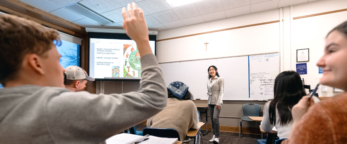 Student raises hand in a classroom 